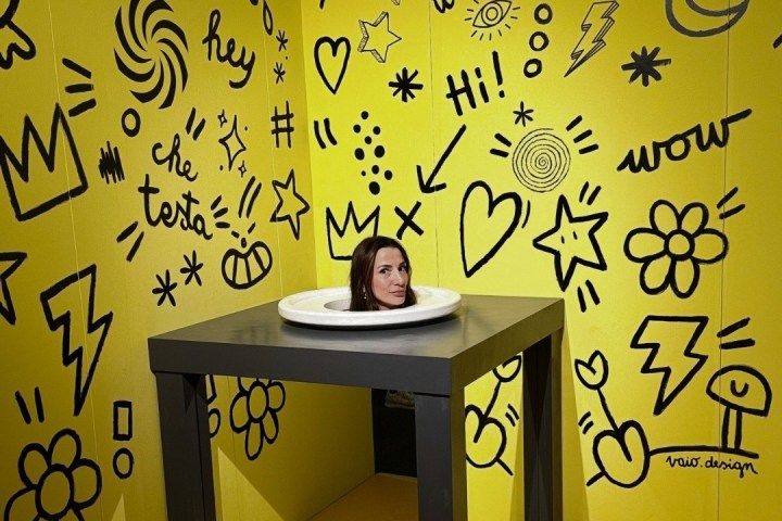 Illusion of woman's head on table in doodled yellow room.