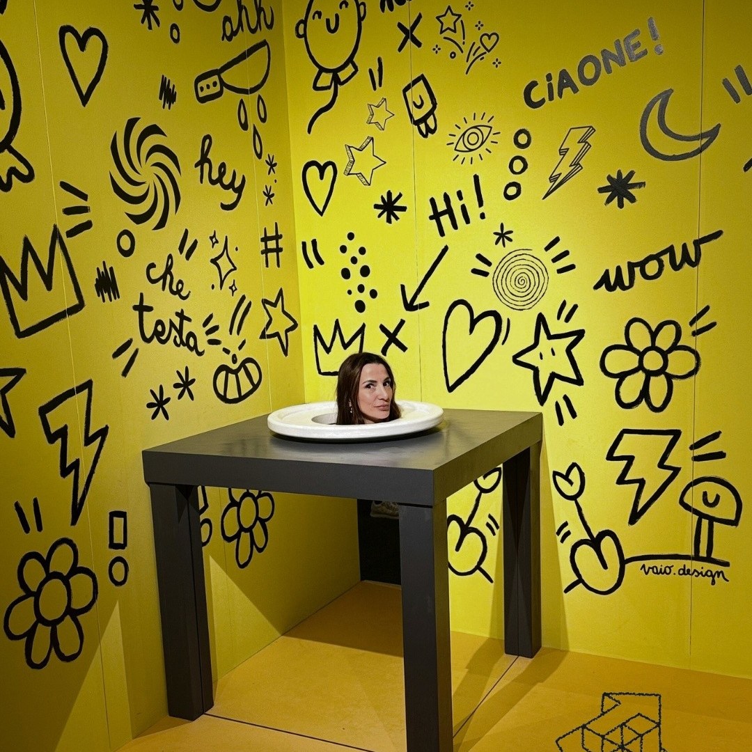 Illusion of woman's head on table in doodled yellow room.