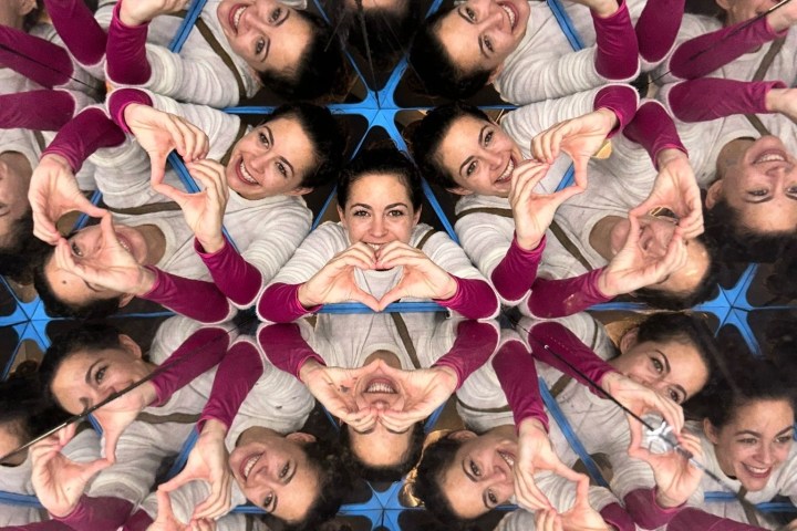 Woman's reflection repeated in a kaleidoscope pattern, making heart shapes with hands.